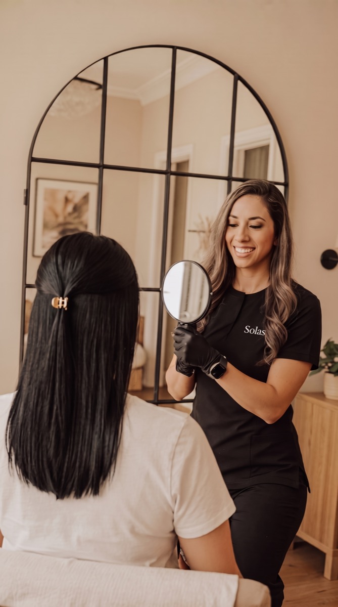 Celeste Cisneros, FNP-BC, showing a patient her natural-looking Botox results in a hand mirror at Solas Health & Wellness in El Paso, TX